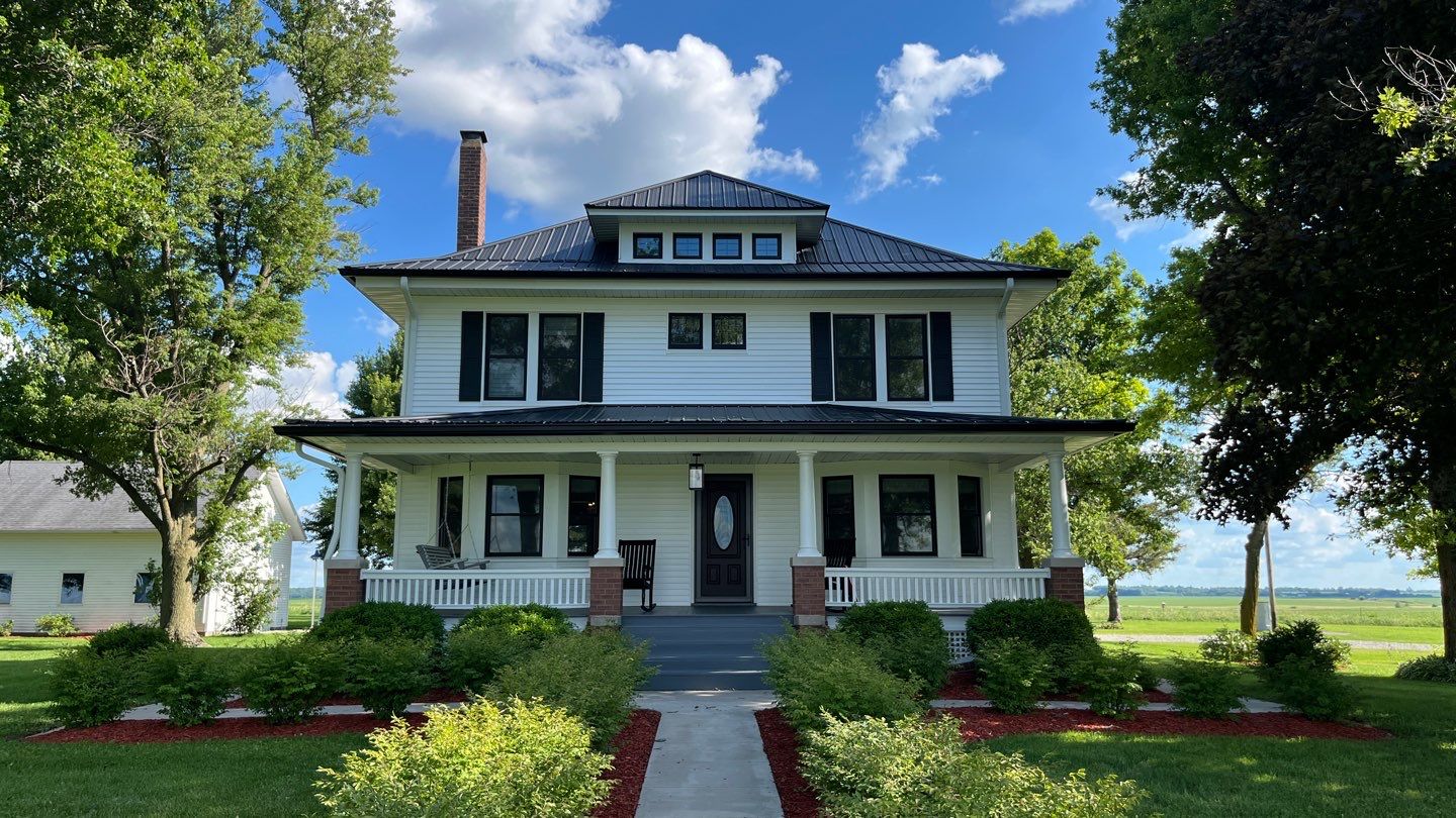 White American Foursquare farmhouse in the Quad Cities with new black seamless gutters and downspouts
